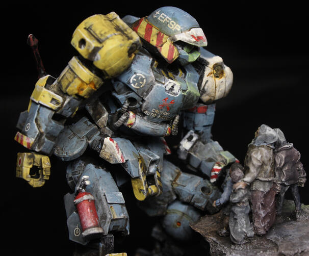 A heavily weathered mech, offering assistance to some disheveled civilians. Main body is pale blue, with strong sections of yellow, red and white, and markings everywhere.