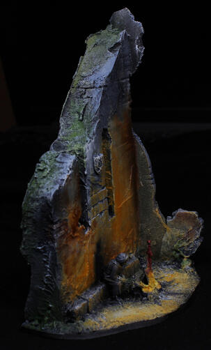 Medieval ruined wall with a bright fire next to it. There's a traveler sitting by the fire, casting a shadow on the wall.