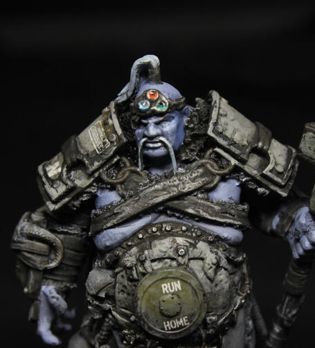 A close-up of a painted model - a giant with pale blue skin, dressed in leather and tank parts.